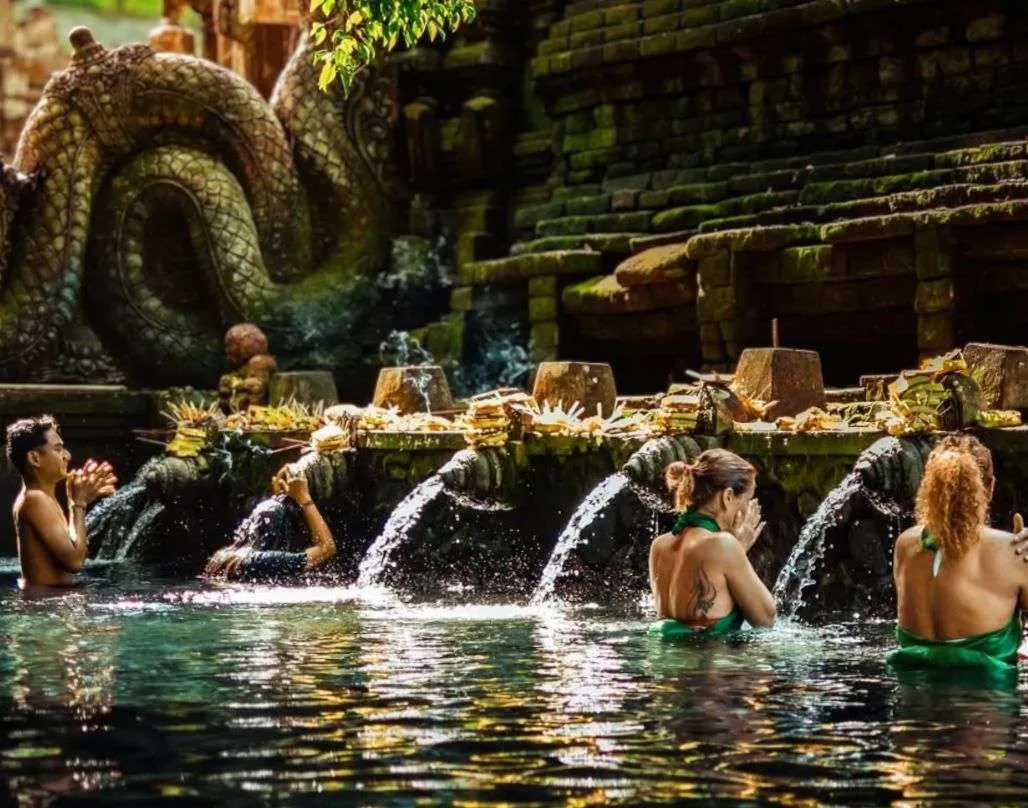 Guests praying and bathing beneath water spouts at a Balinese temple spring